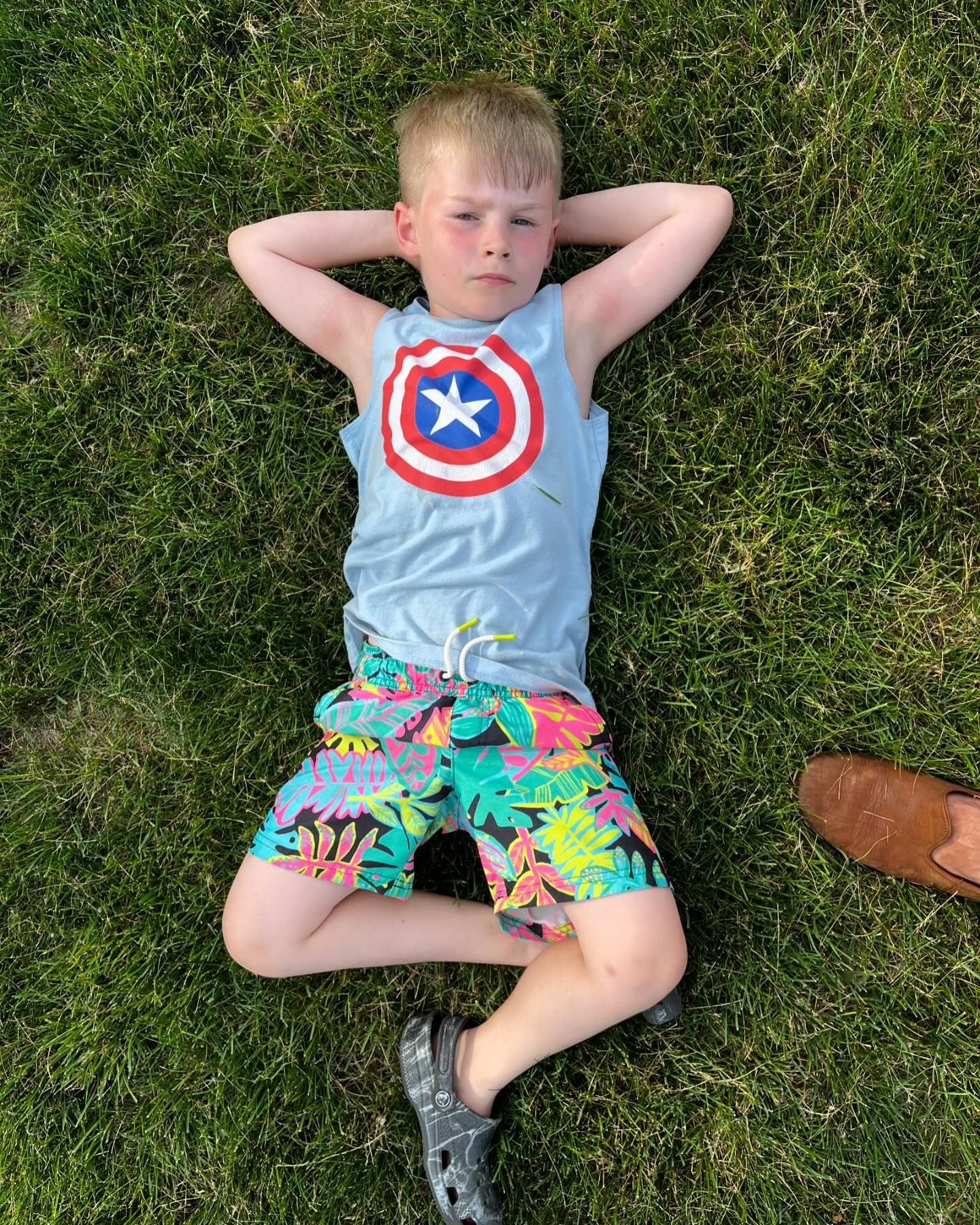 A seven year old laying in the grass exuding the confidence and chill of a rockstar